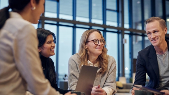 People talking and smiling working at the table with laptops and mugs