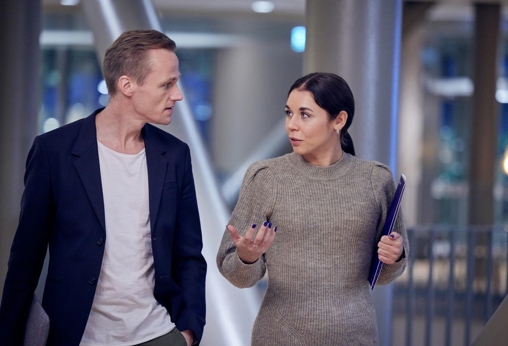 Man and woman walk and talk holding folder